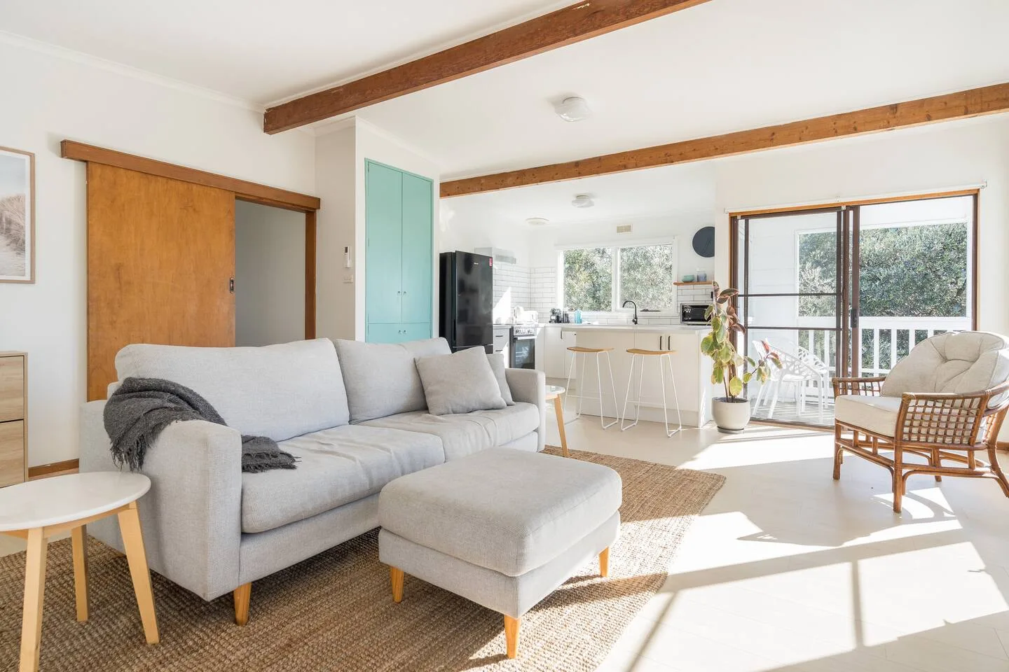 Una sala luminosa con asientos y una cocina abierta junto a grandes ventanas.