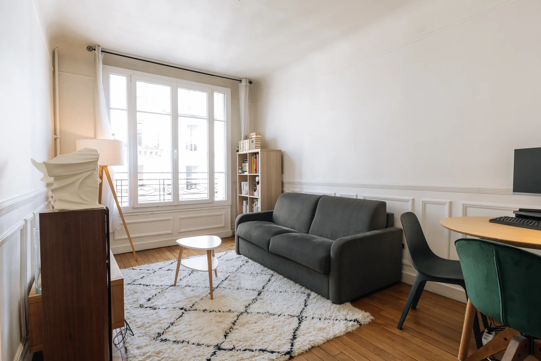 Una sala luminosa con asientos oscuros, una ventana amplia y un escritorio.