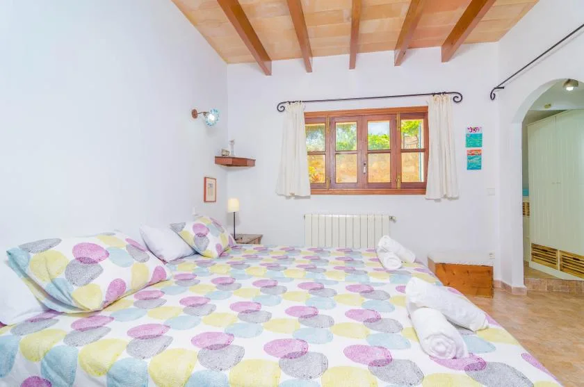 Un dormitorio con una cama bajo una ventana con marco de madera.