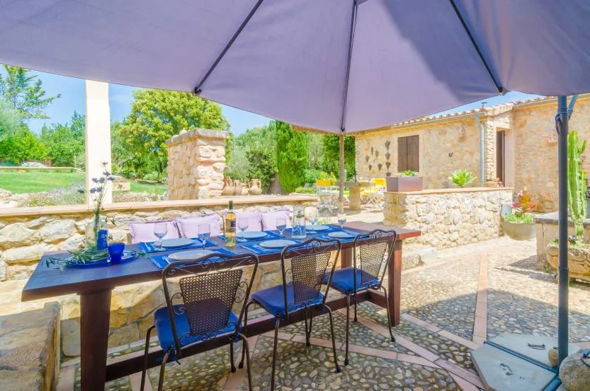 Una zona de comedor al aire libre está bajo una sombrilla junto a un edificio de piedra.