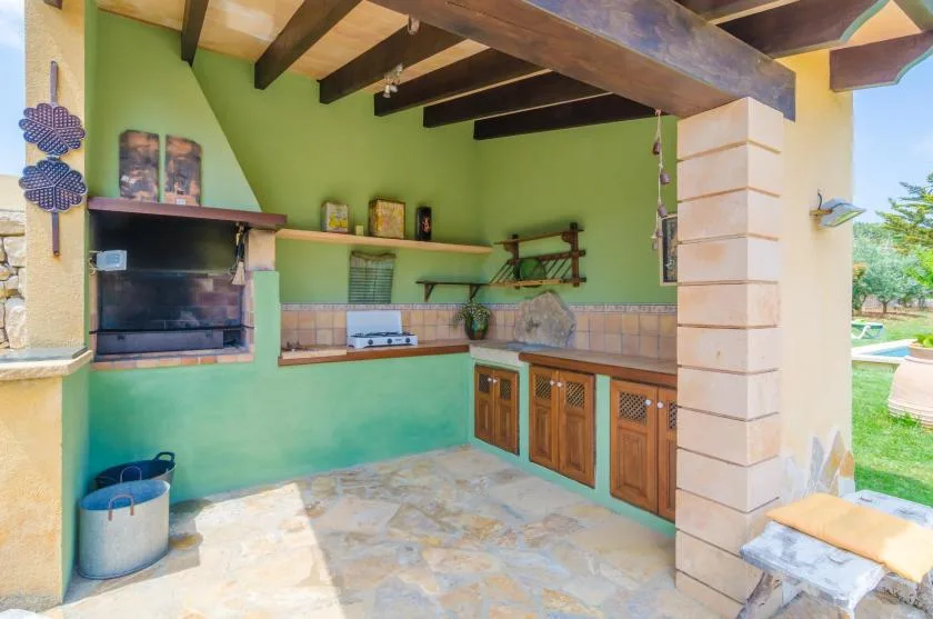 Una cocina exterior con una parrilla empotrada y gabinetes de madera.