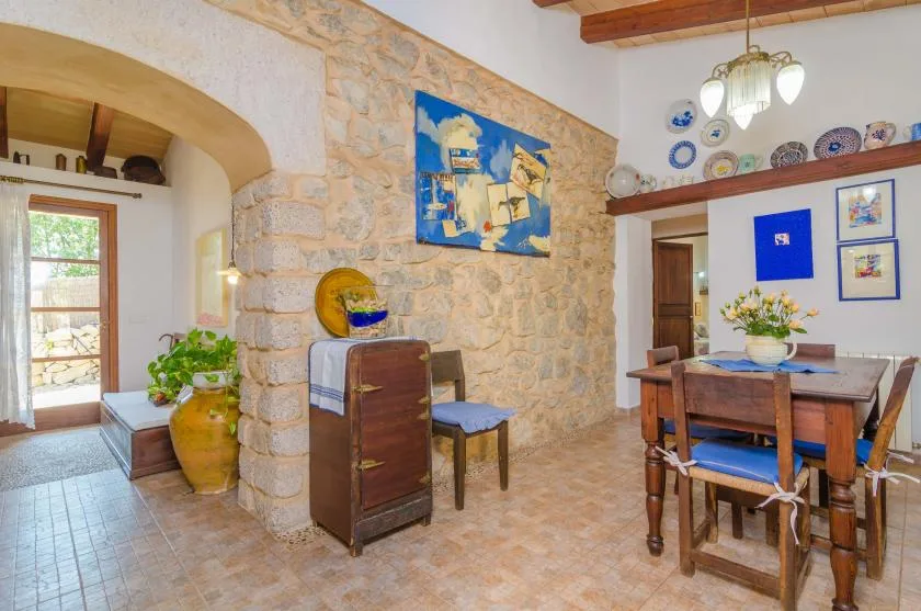 Un comedor rústico con una mesa de madera y sillas junto a una pared de piedra.