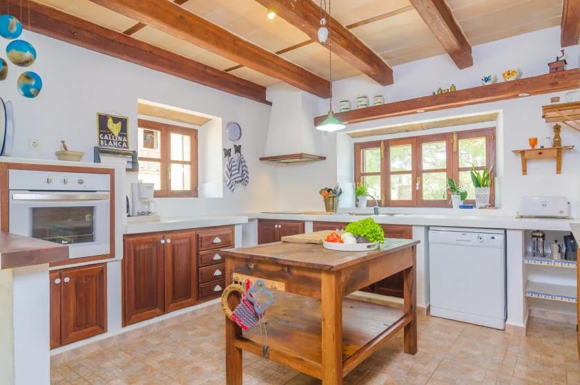 Una cocina luminosa con gabinetes de madera, una isla central y ventanas.