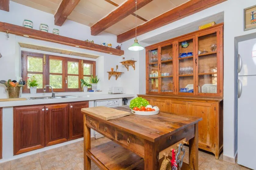 Una cocina con gabinetes de madera, una mesa central y una ventana sobre el fregadero.