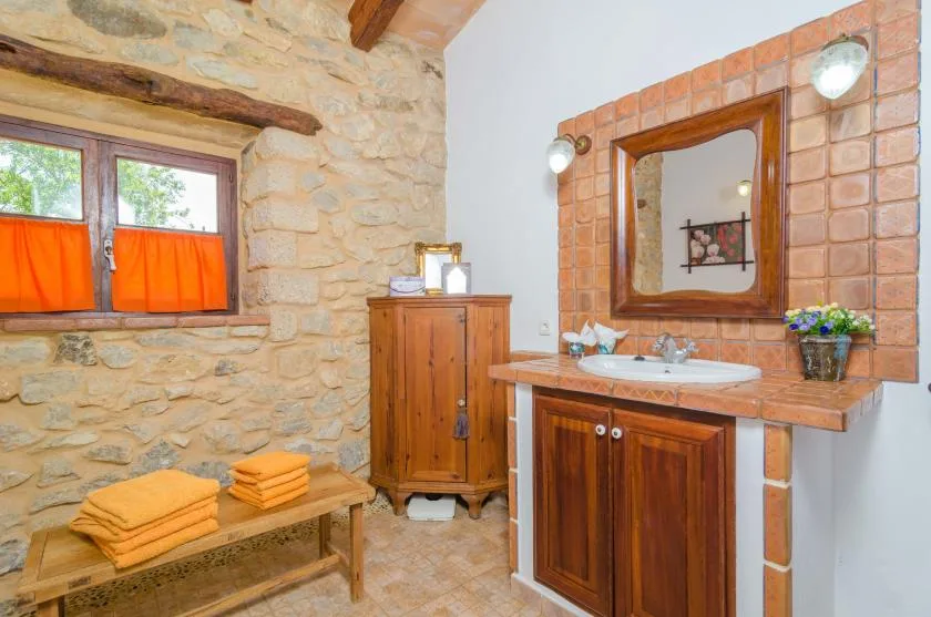 Un baño rústico con una pared de piedra, un mueble de madera y un lavabo.