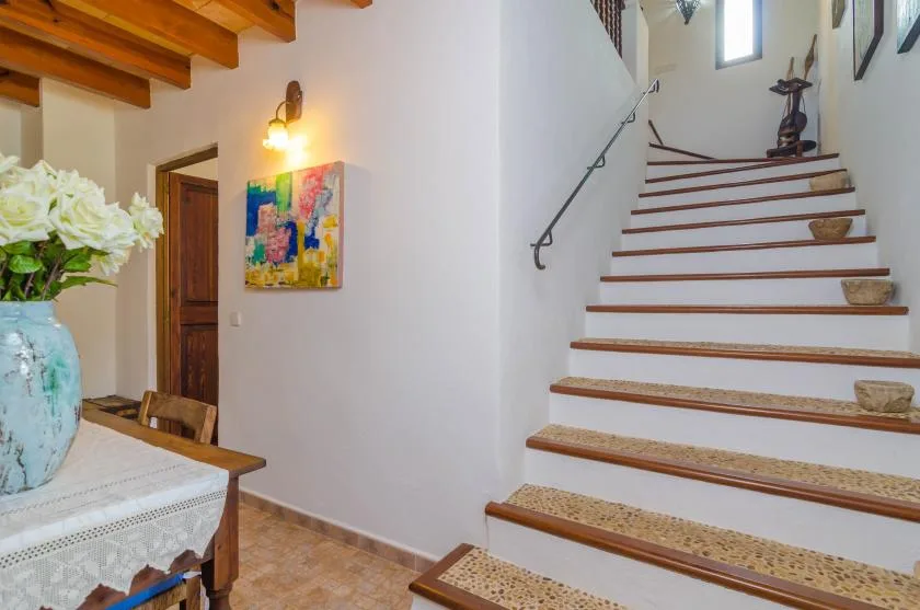 Una escalera interior con peldaños estampados sube junto a un comedor.
