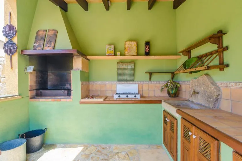 Una cocina exterior verde con parrilla integrada, encimera y cocina.
