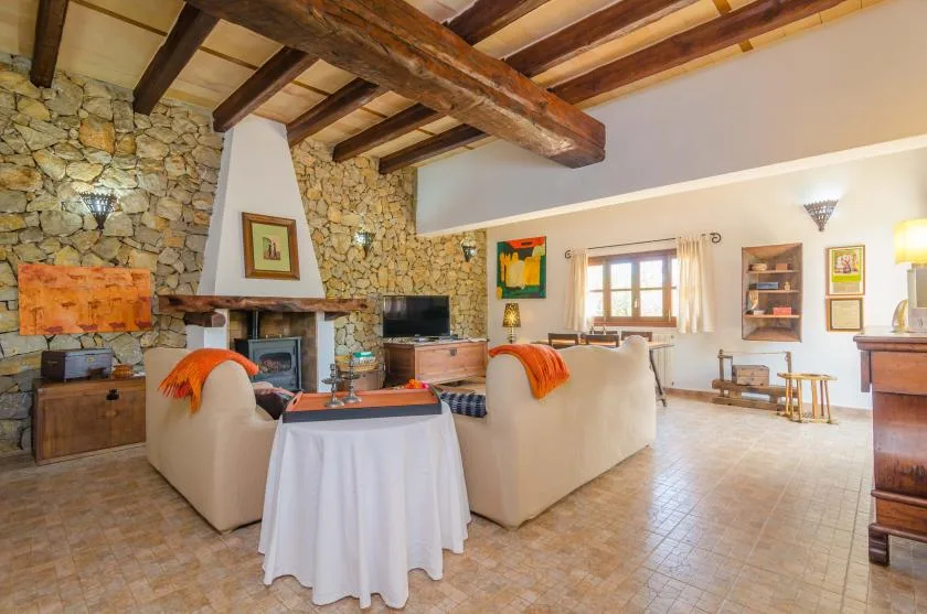 Una sala de estar con paredes de piedra, vigas de madera expuestas y asientos junto a una chimenea.