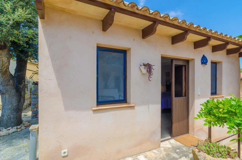 Exterior de estuco blanco con una ventana de marco azul y una puerta abierta.