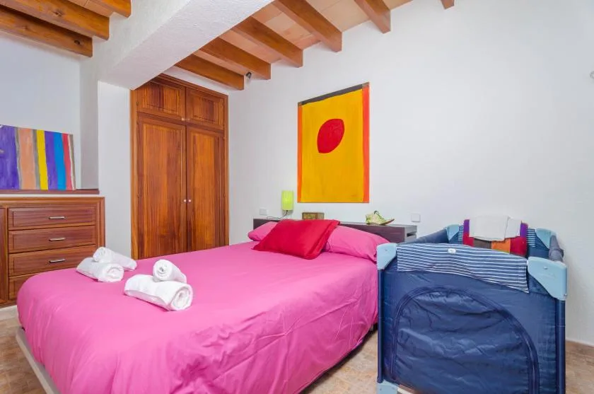 Un dormitorio con una cama rosa y una cuna azul al lado.