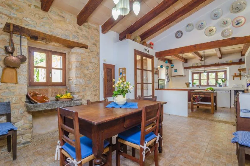 Una cocina y comedor rústicos con una mesa de madera bajo vigas expuestas.