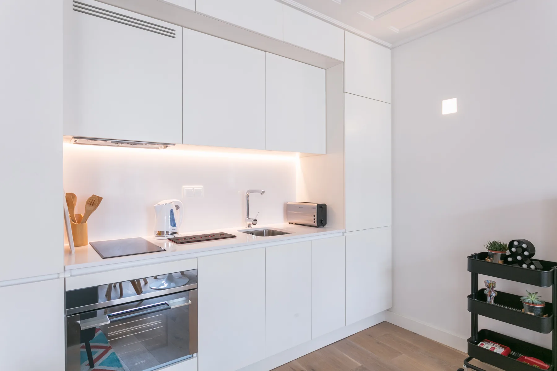 Una cocina moderna blanca con horno empotrado y electrodomésticos sobre la encimera.