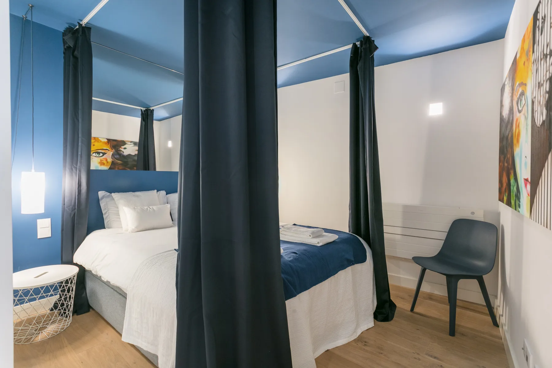 Dormitorio con una cama, cortinas oscuras y una silla.