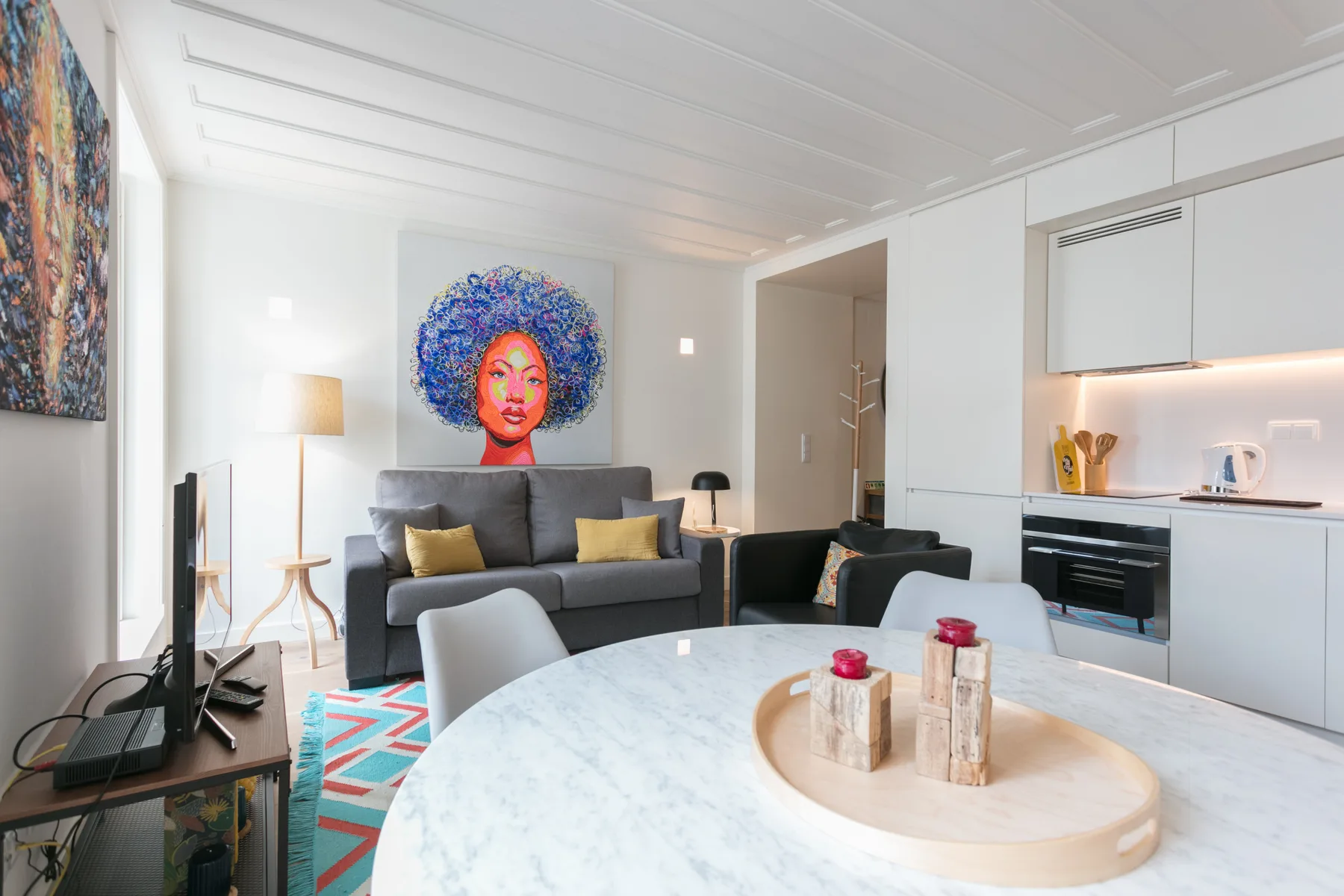 Una luminosa sala de estar con sofá, mesa de comedor y cocina integrada.
