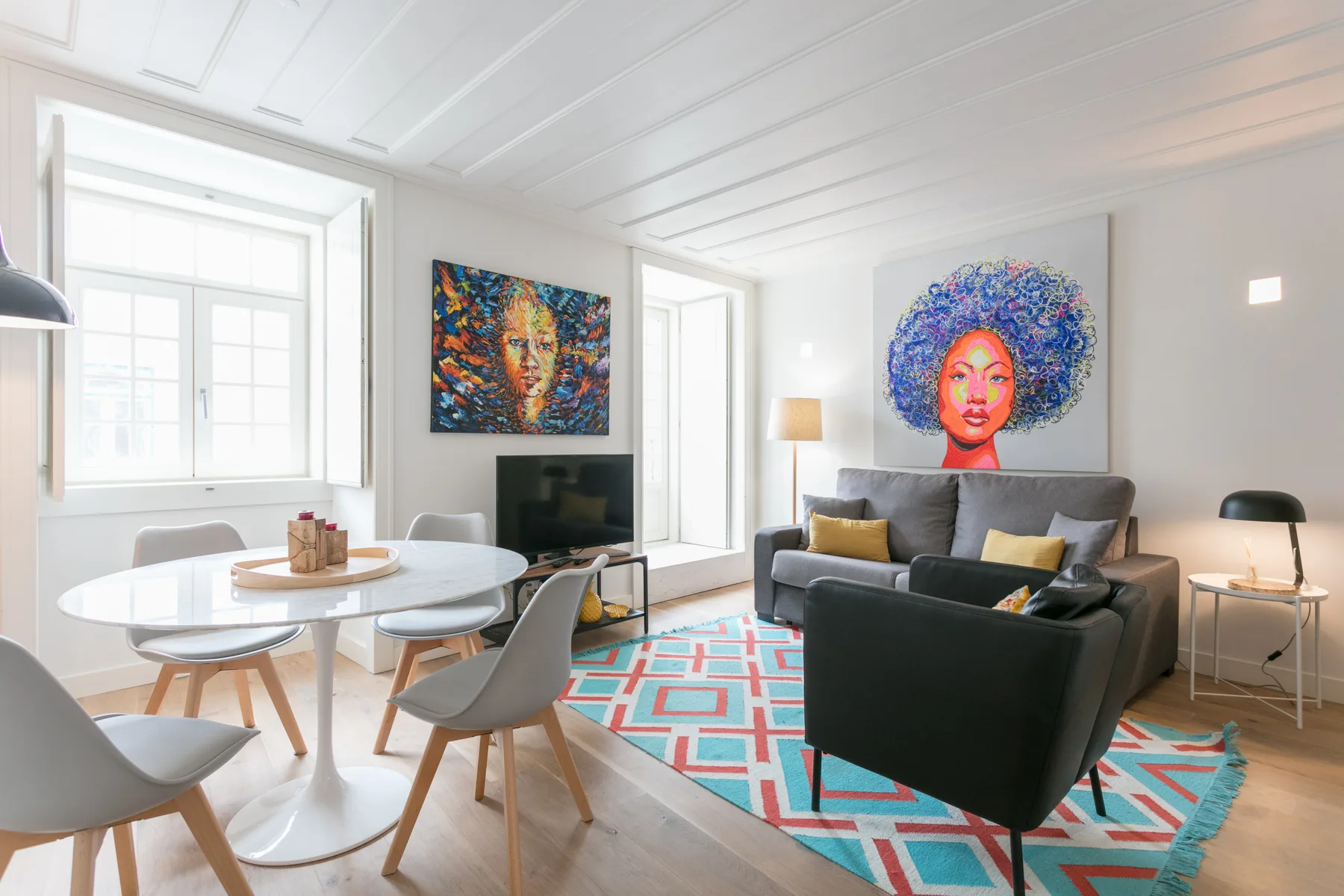 Una sala de estar luminosa con asientos, una mesa de comedor y arte colorido en las paredes.