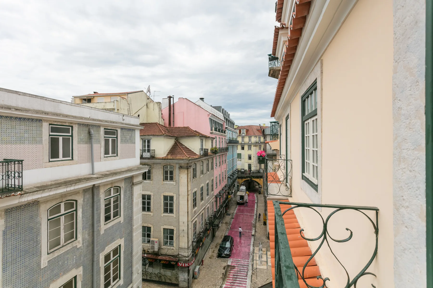 Una calle estrecha bordeada de edificios de tonos pastel, vista desde un balcón.