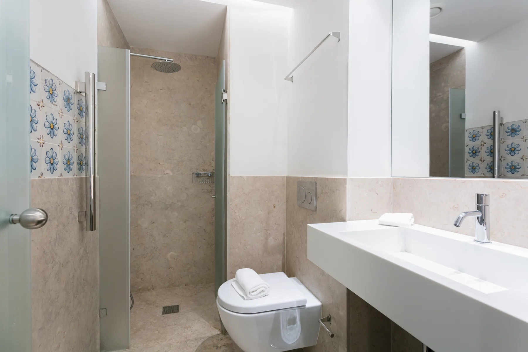 Un baño moderno con ducha, inodoro y un largo lavabo blanco.