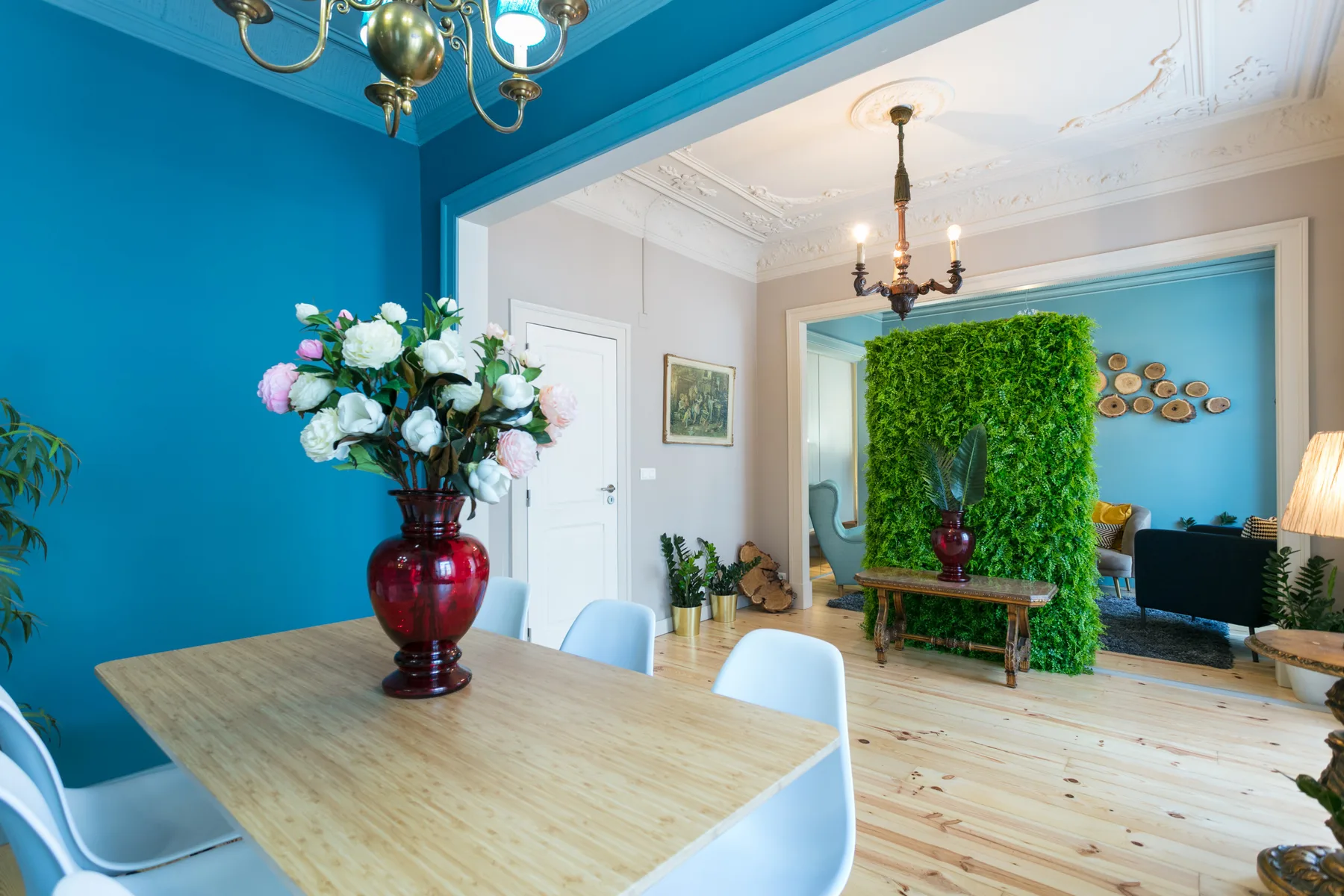 Un comedor se abre a una sala de estar con una pared de plantas verdes.