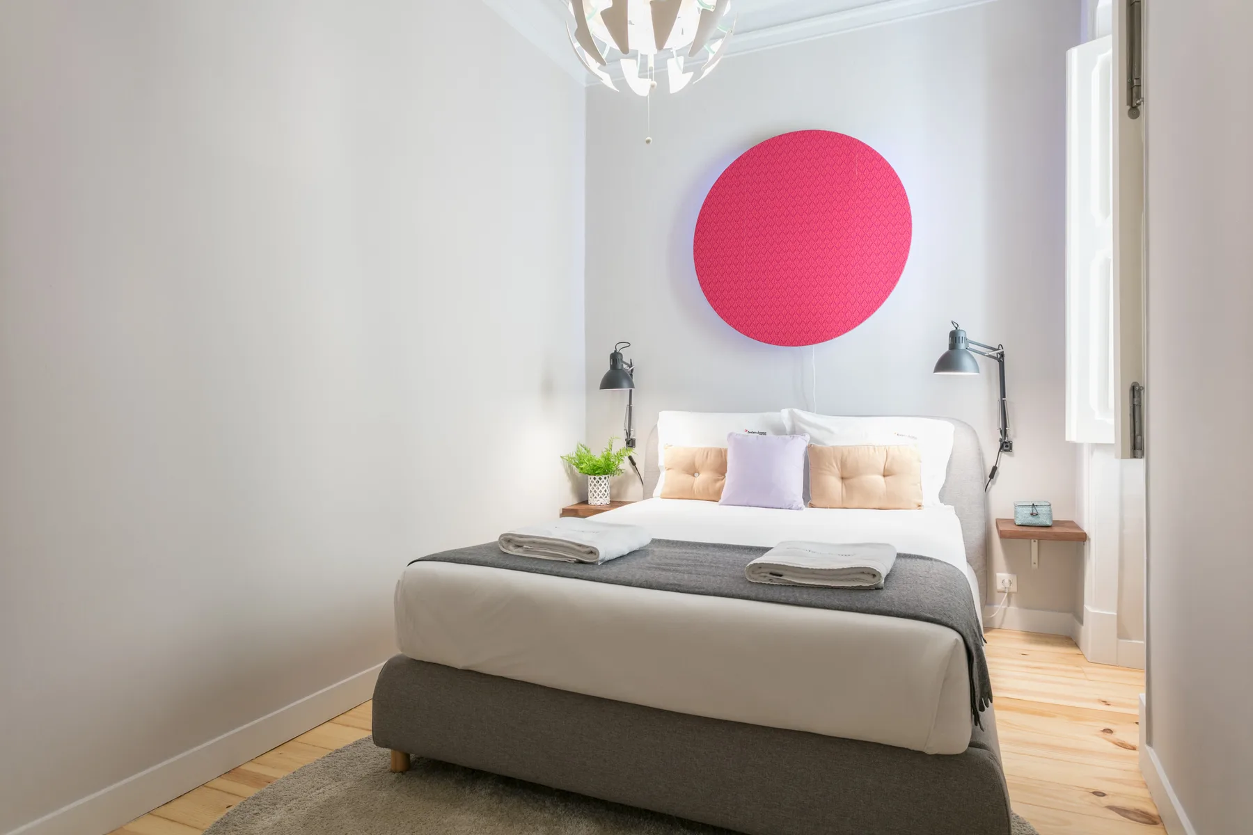 Un dormitorio luminoso con una cama bajo una gran decoración circular en la pared.