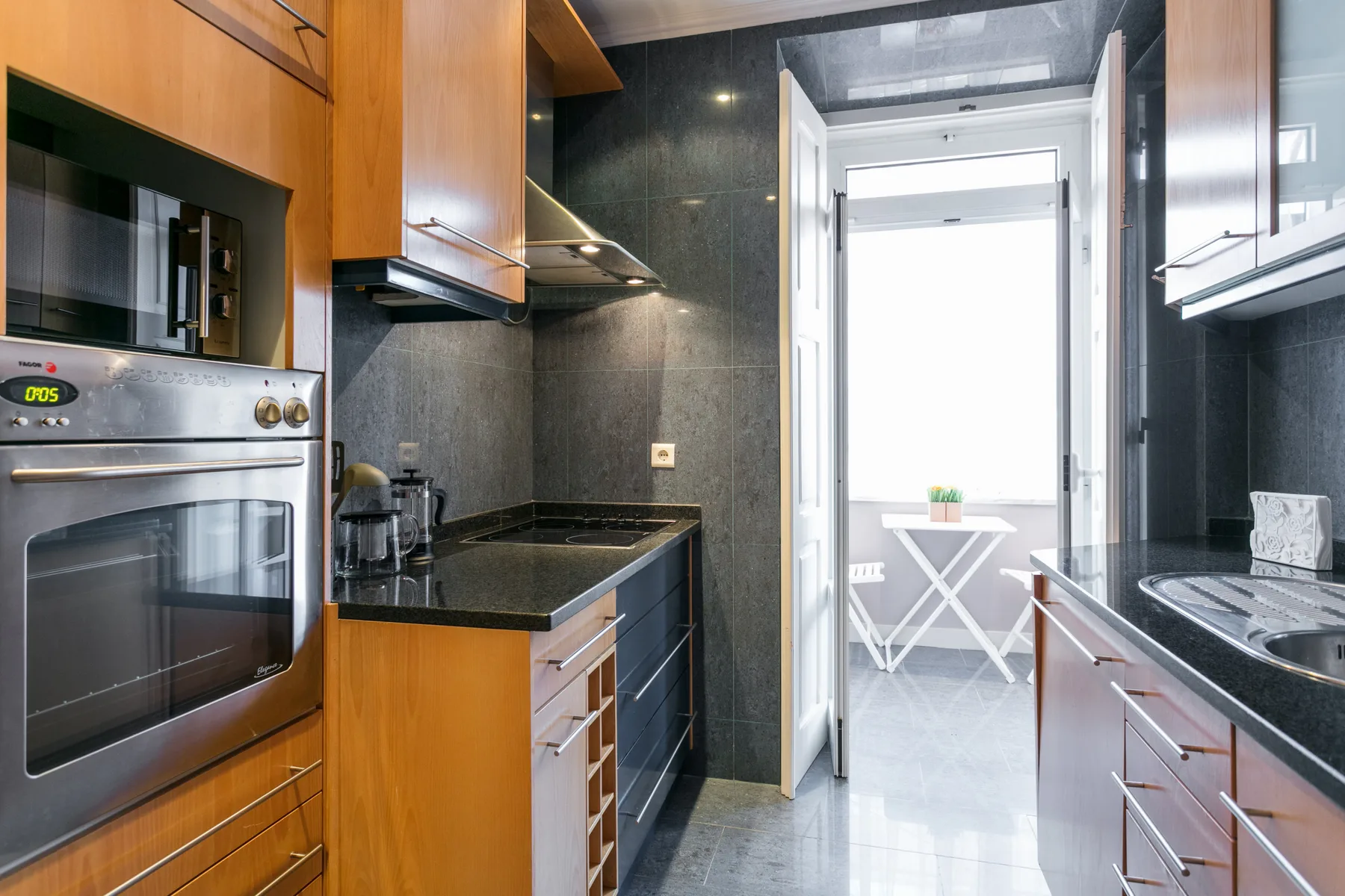 A galley kitchen with dark countertops and wooden cabinets.
