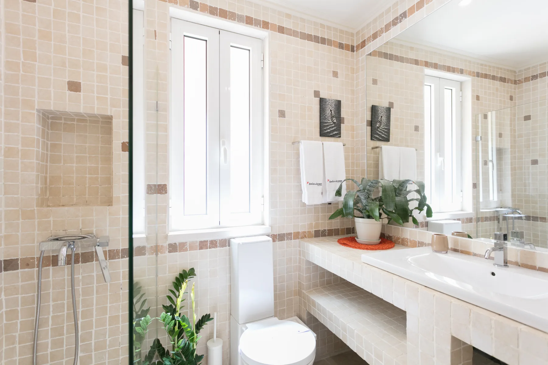 Un baño revestido de azulejos con bañera, inodoro y un largo lavabo.