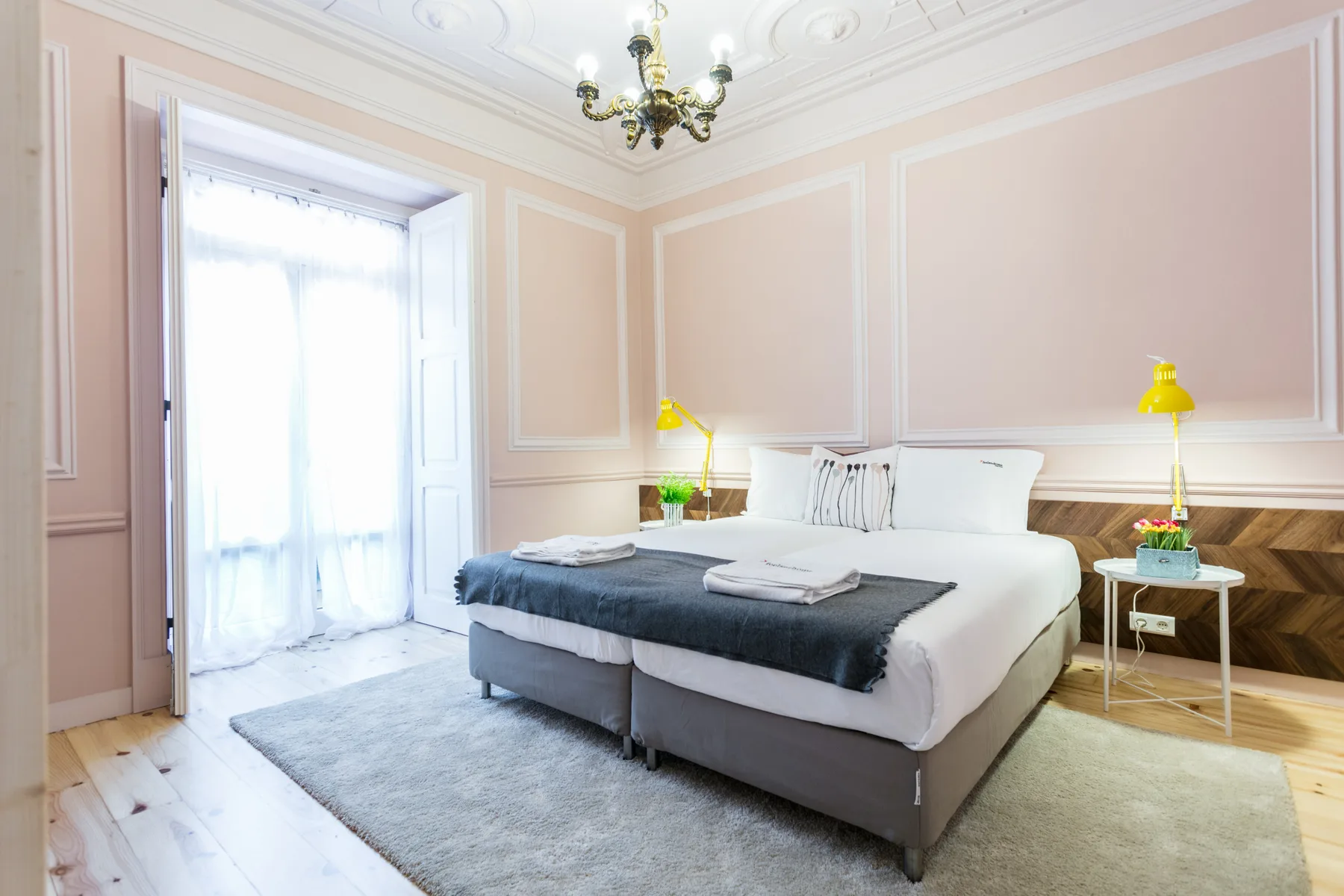 Un dormitorio con una cama bien hecha y ventanas grandes.