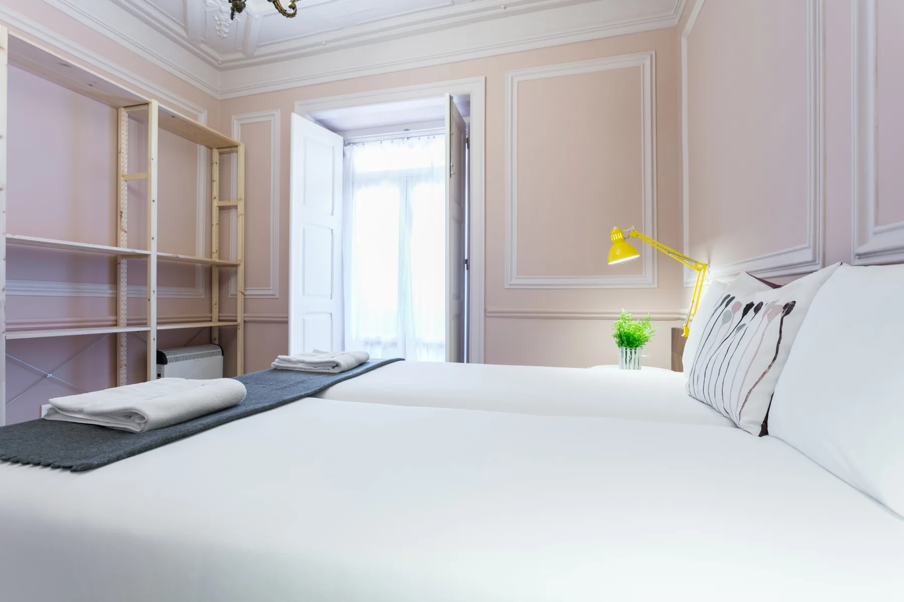Un dormitorio con una cama bien hecha, estanterías empotradas y una lámpara amarilla.