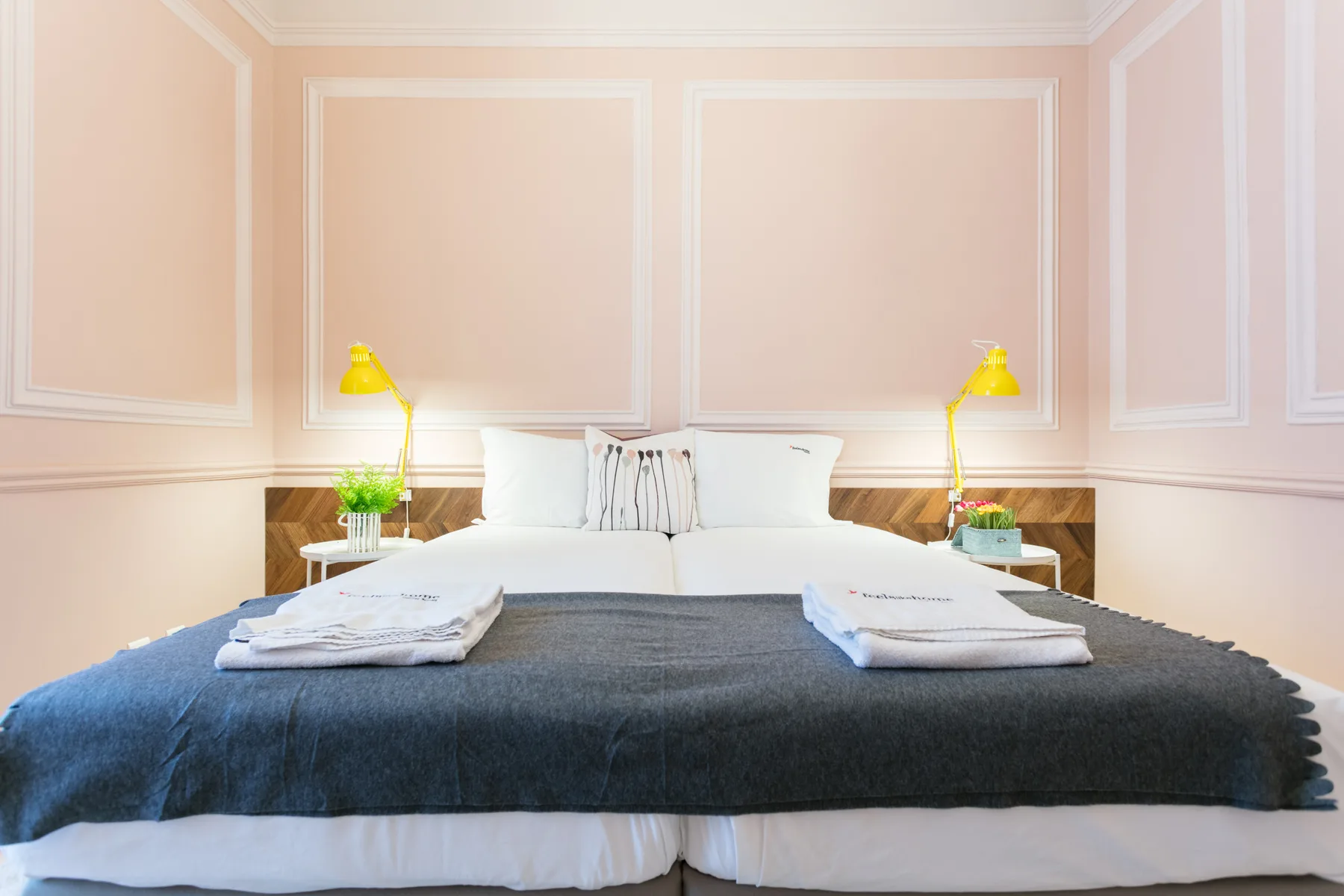 Un dormitorio con una cama bien hecha y lámparas de noche a juego.