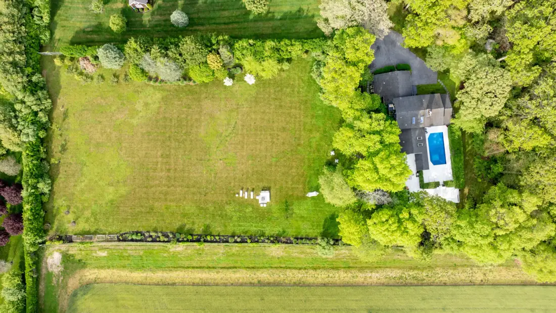 Vista aérea de una casa junto a un amplio césped y árboles alrededor.