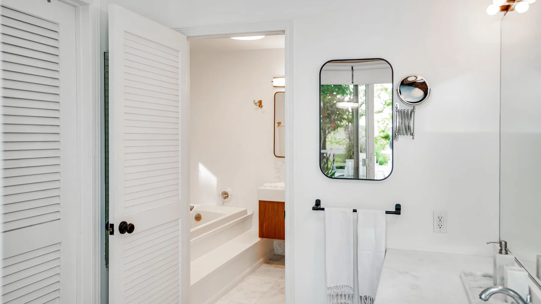 Un baño luminoso con bañera, tocador y espejo de pared.