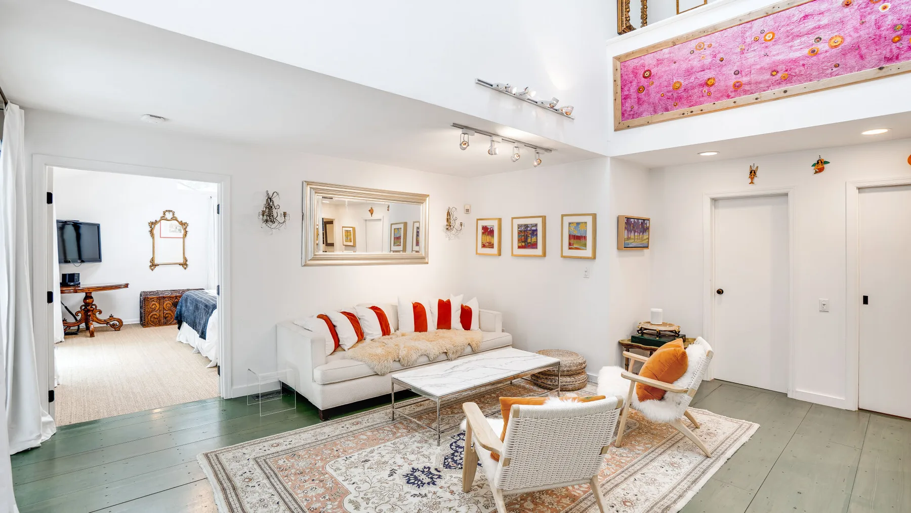 Una sala luminosa con asientos blancos y obras de arte coloridas en las paredes.