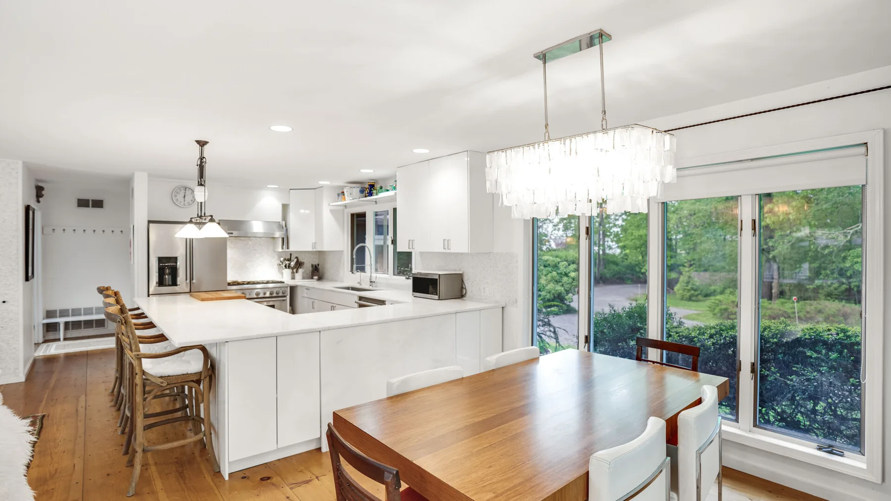 Una cocina y comedor luminosos con una mesa de madera junto a grandes ventanas.
