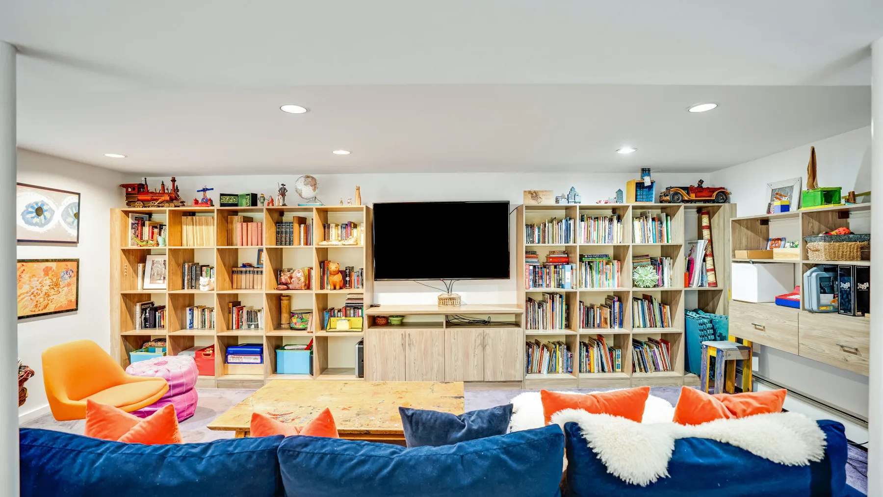 Una sala de juegos colorida con estanterías, un televisor y asientos.