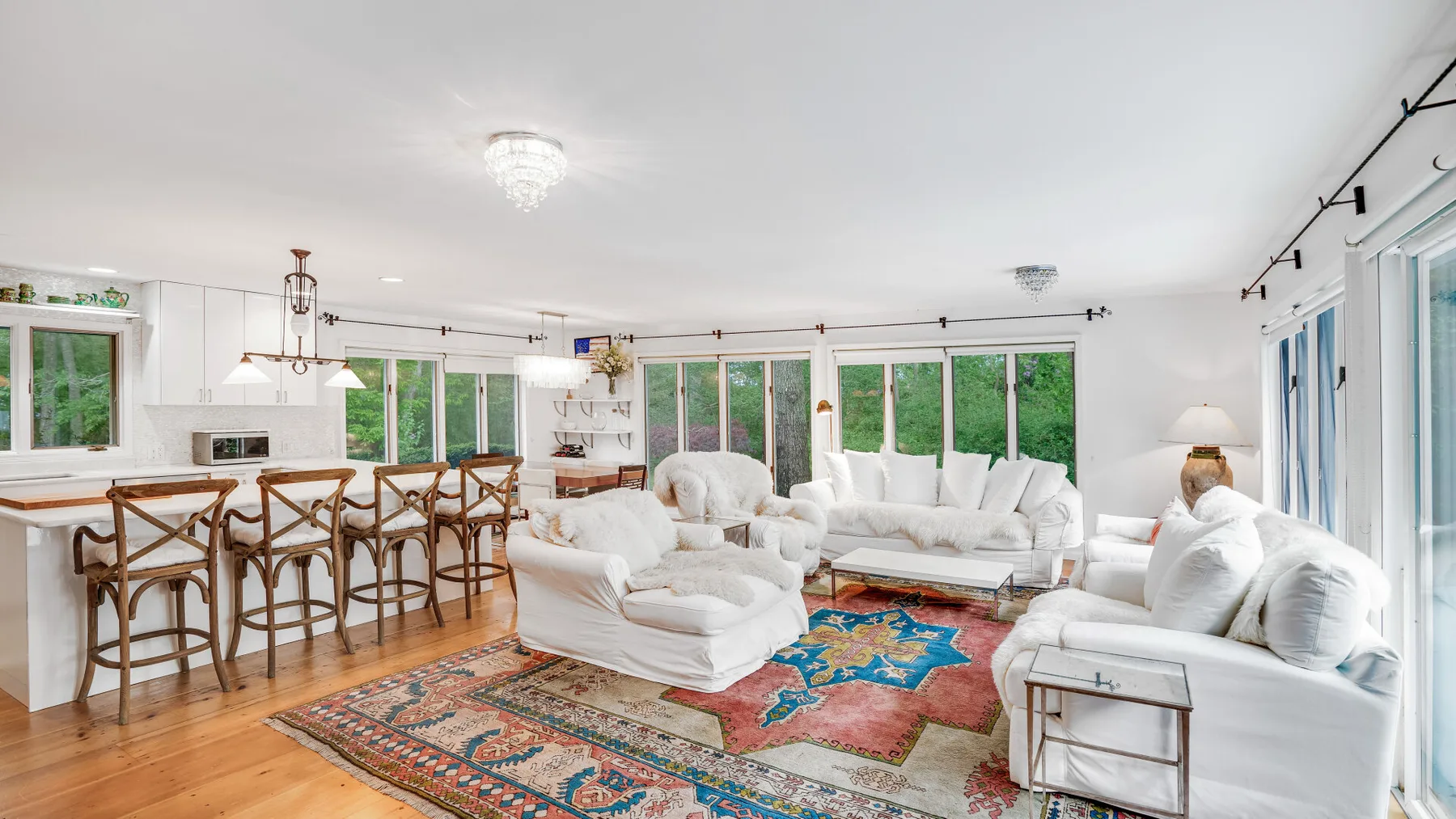 Una sala luminosa con asientos blancos alrededor de una alfombra estampada de colores.
