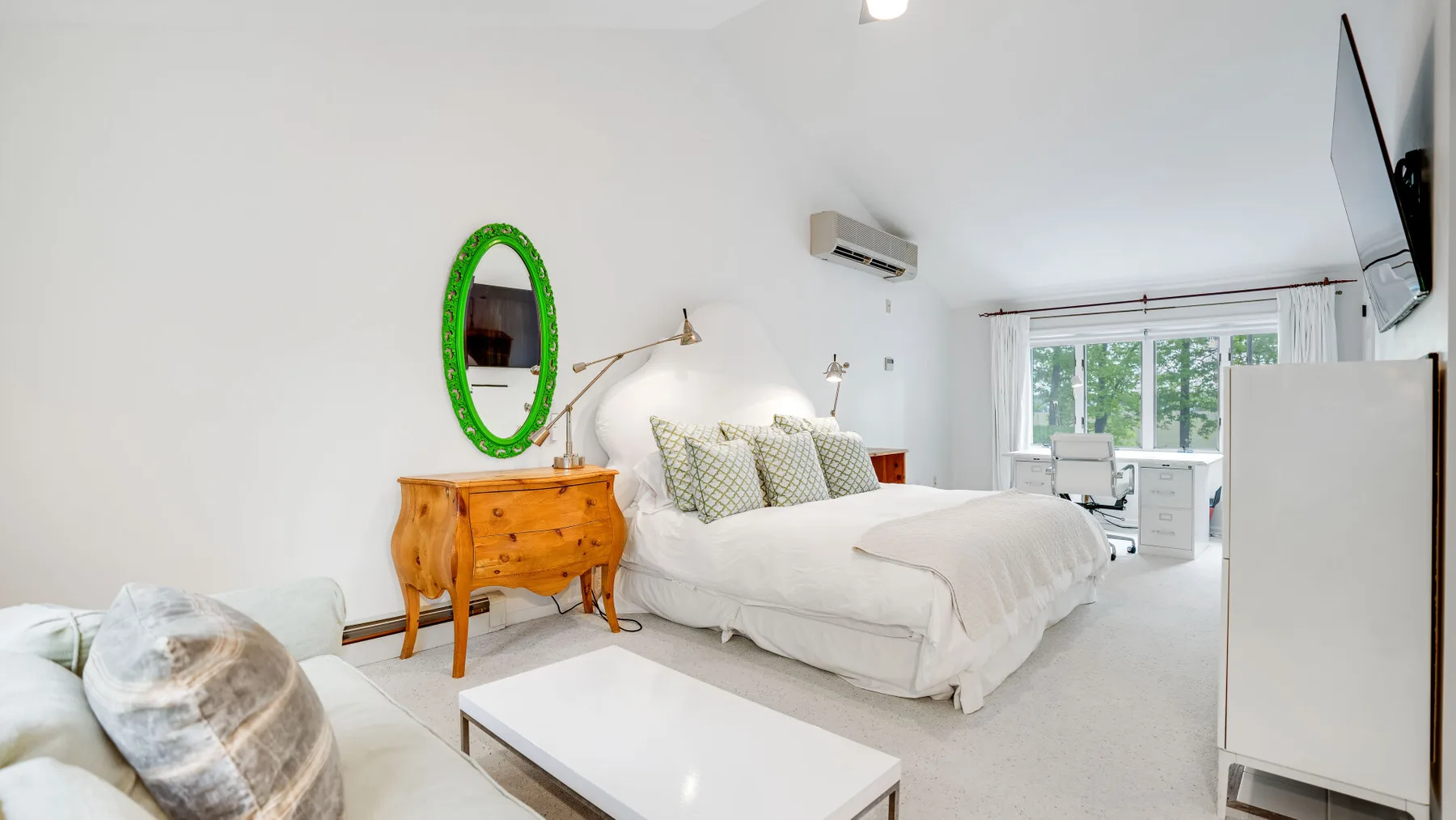 Un dormitorio con una cama, una cómoda de madera y una ventana con vista a la vegetación.