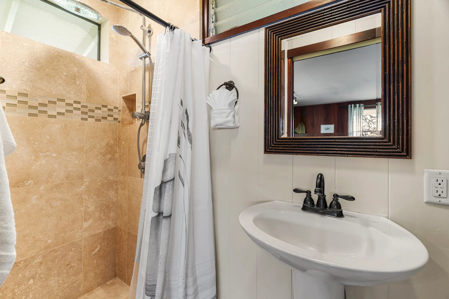 Un baño con lavabo, espejo y ducha con cortina.