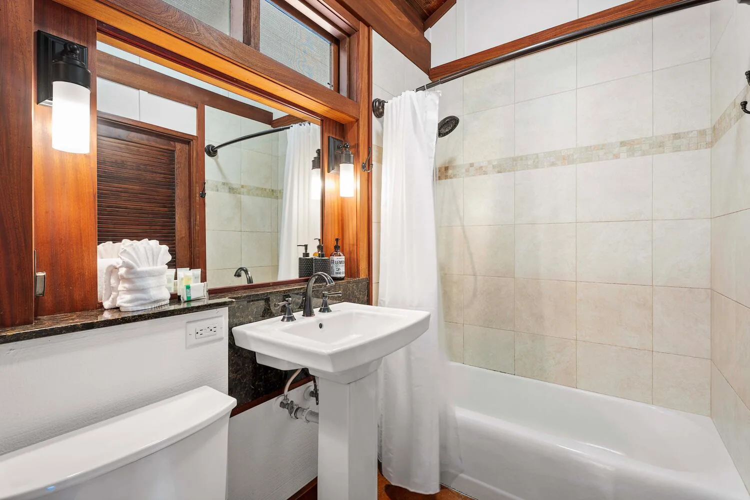 Un baño con lavabo, inodoro y bañera detrás de una cortina de ducha.
