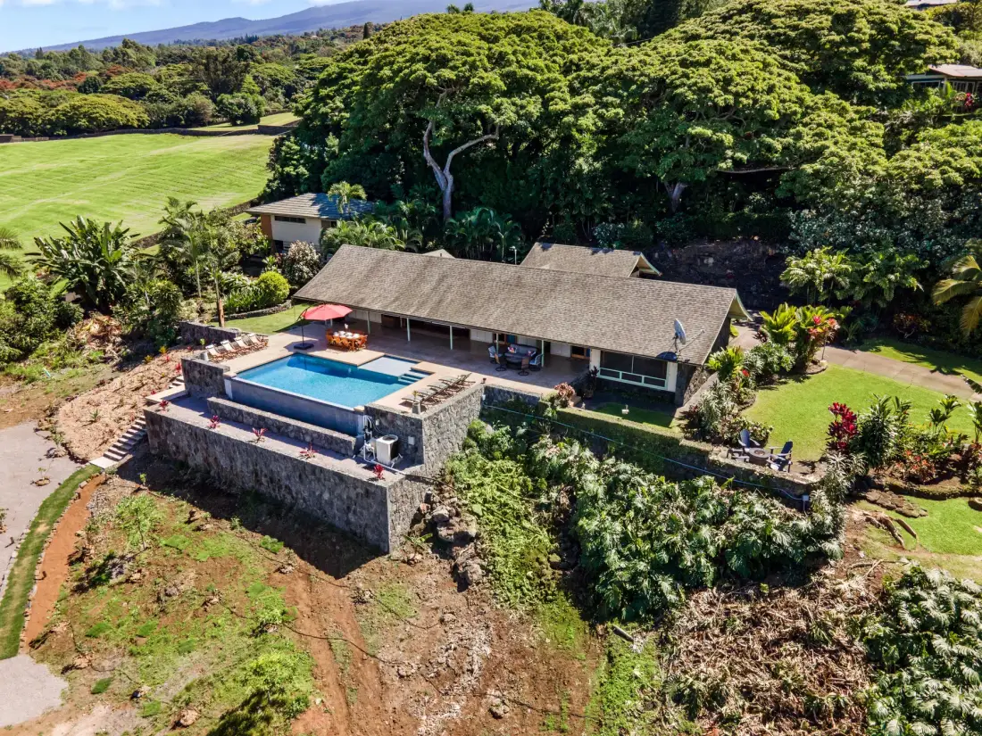 Vista aérea de una casa junto a una piscina, rodeada de vegetación.