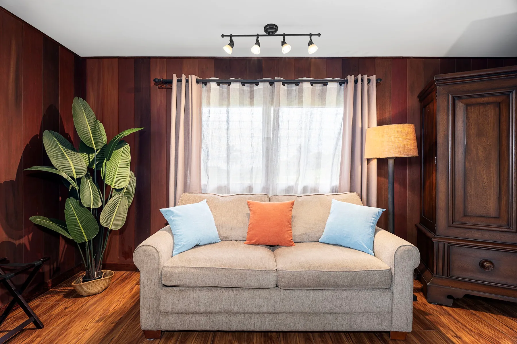 Una sala de estar con un sofá bajo una ventana luminosa con cortinas.