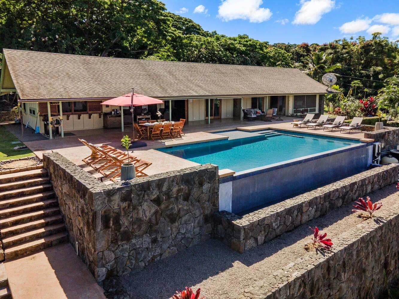 Una piscina y un patio con asientos junto a un edificio de una planta.