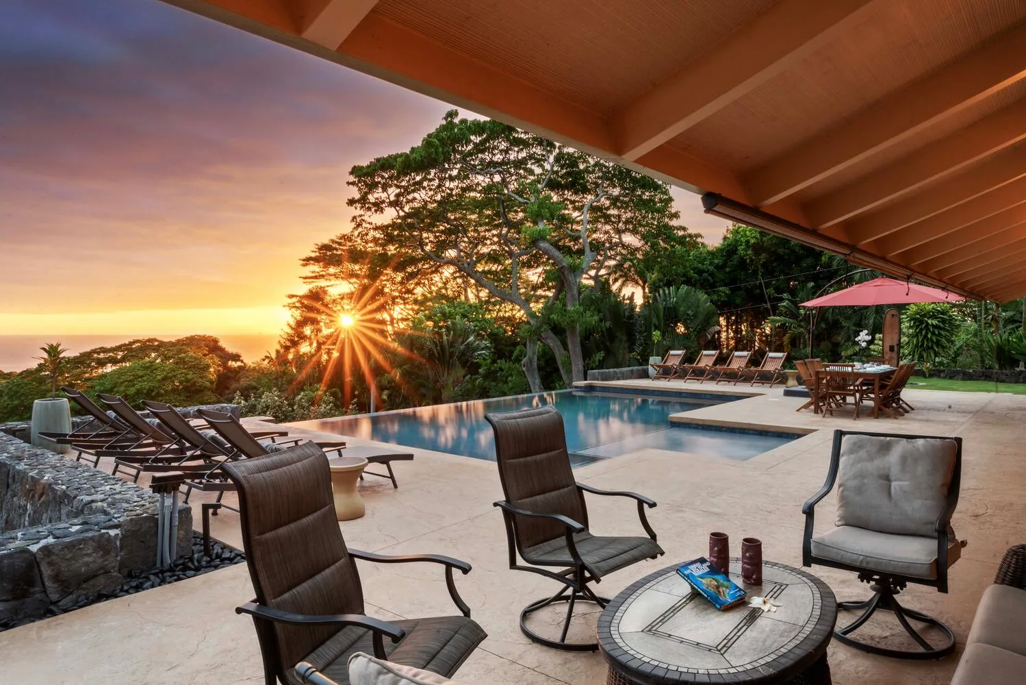 Un patio junto a una piscina al aire libre, con asientos y vistas al atardecer.