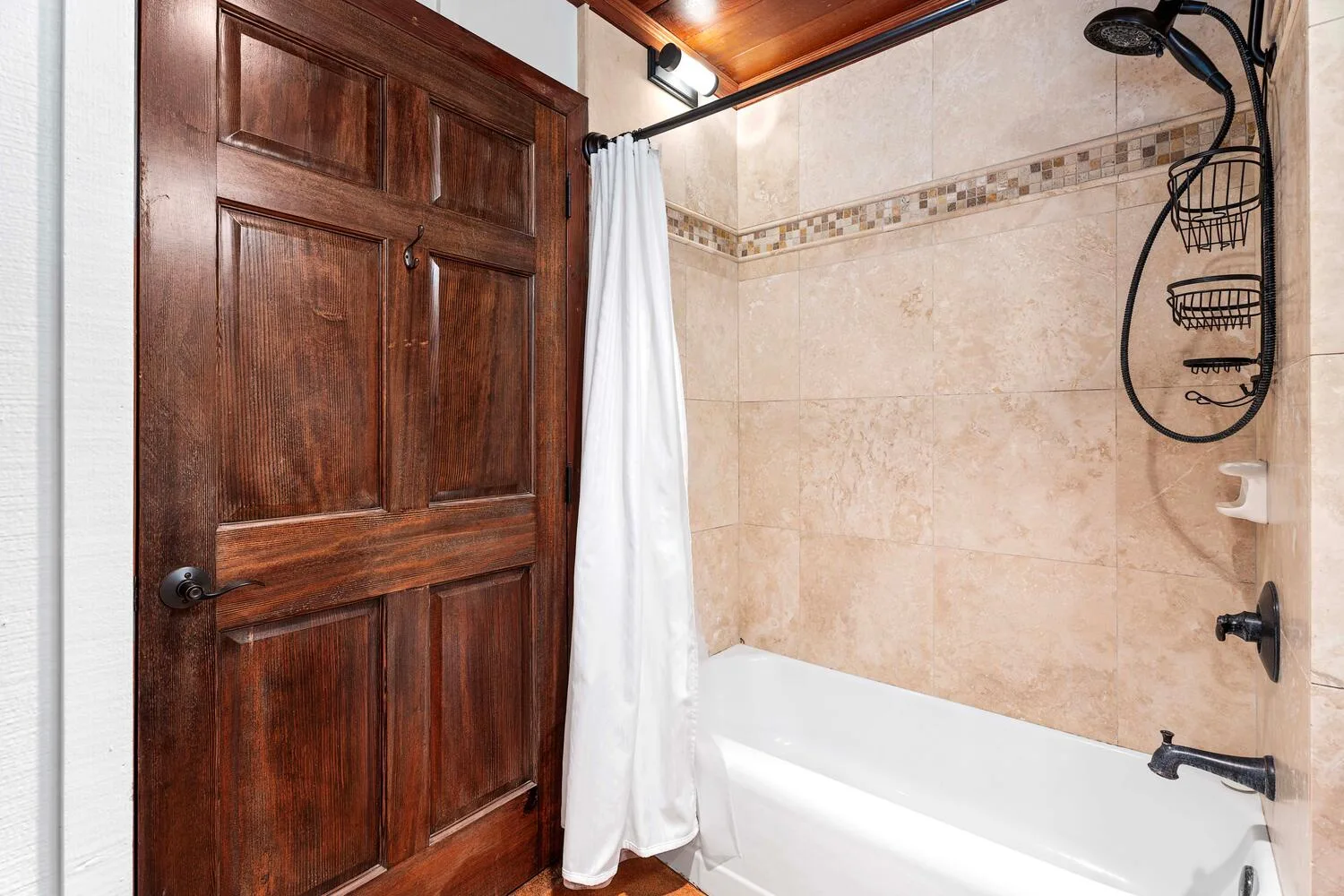 Un baño alicatado con bañera, ducha y cortina blanca.