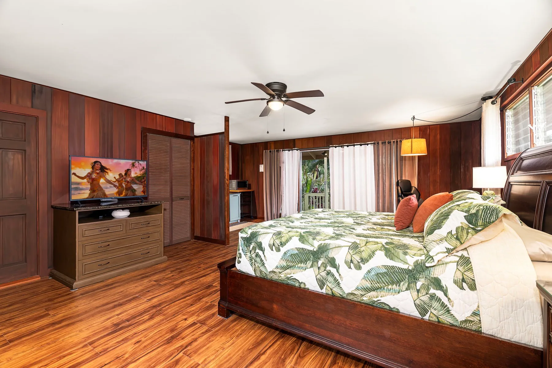 Un dormitorio con una cama de madera y ropa de cama con hojas verdes.