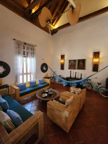 A living room with wicker seating, a hammock, and exposed wooden ceiling beams.
