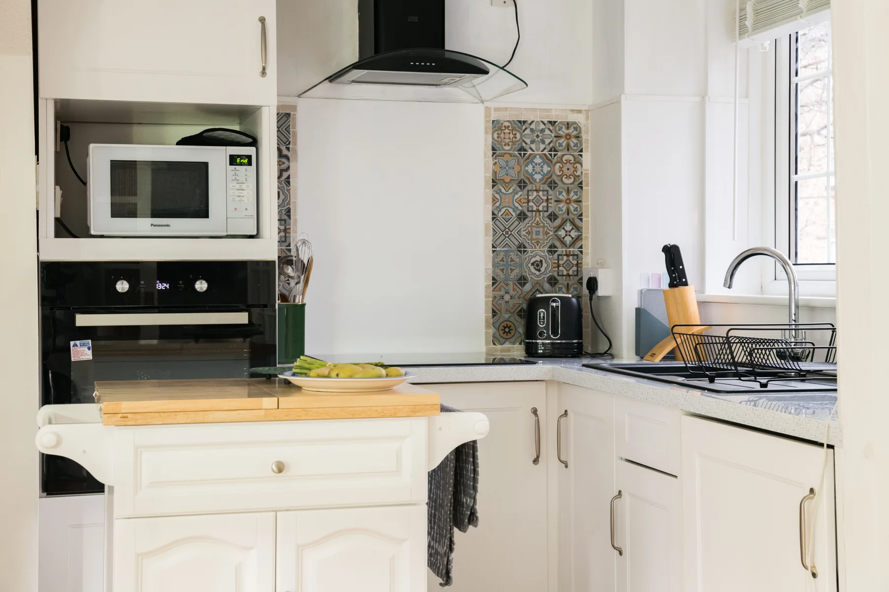 Una cocina luminosa con gabinetes blancos, una encimera y una isla central.