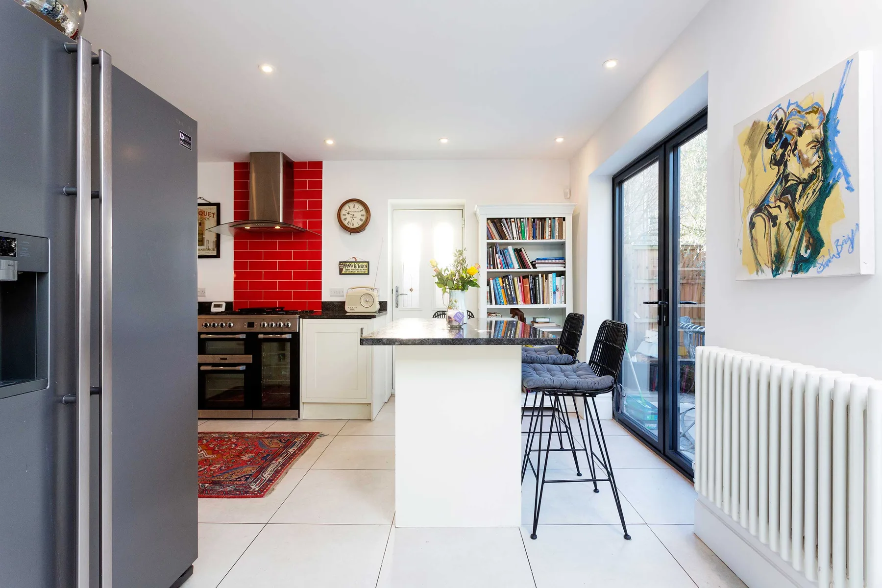 A bright kitchen with a central island and seating beside large windows.