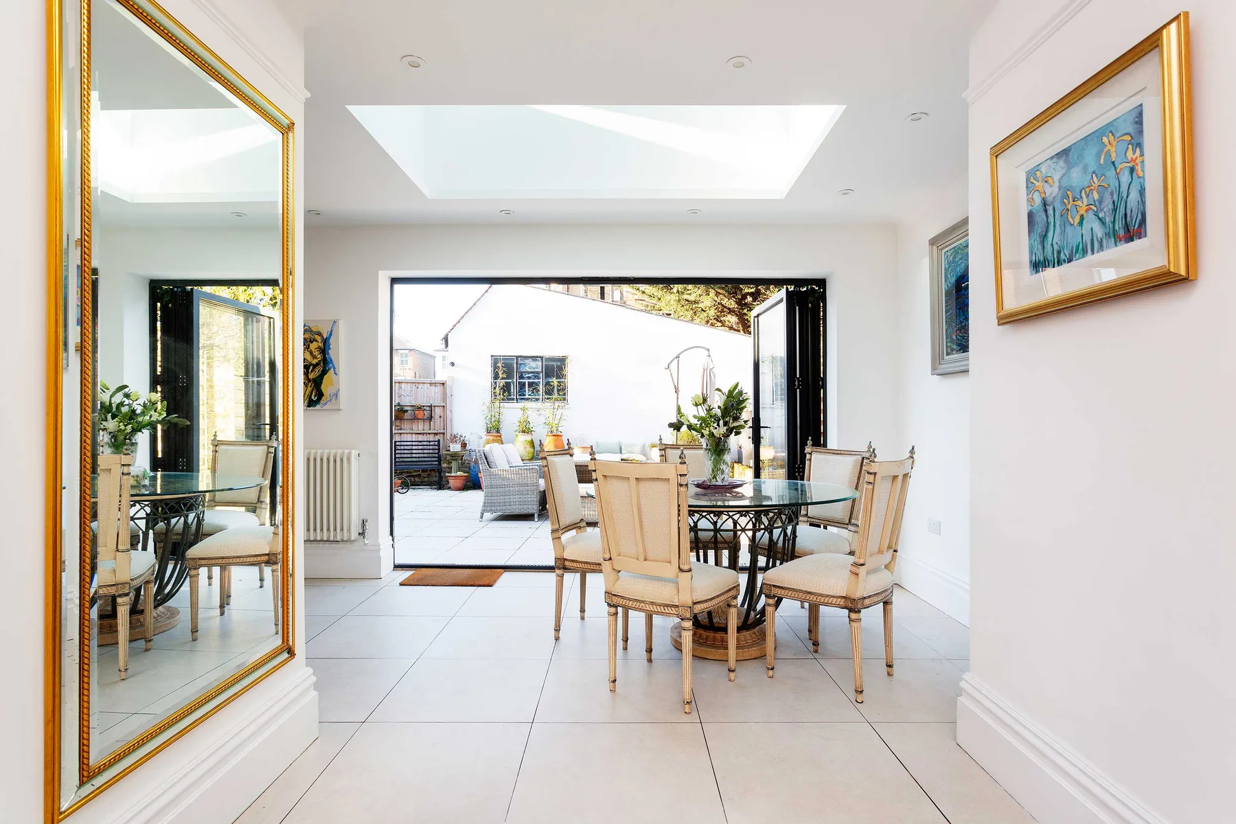 A bright dining area opens onto a patio, with a glass table and seating.