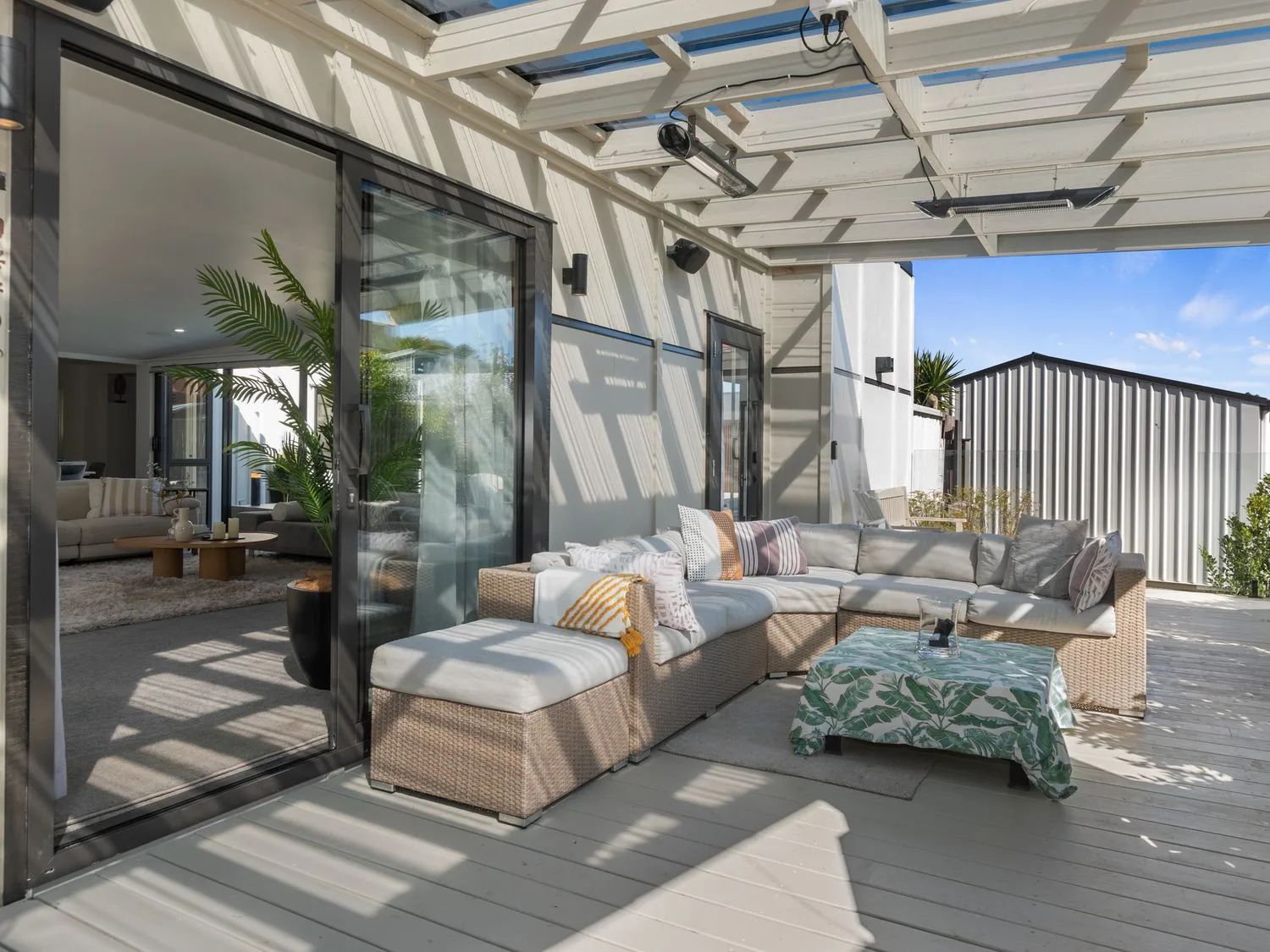 Una zona de estar al aire libre con un sofá y una mesa de centro en Sun Kissed Pool Villa - Mangawhai Heads