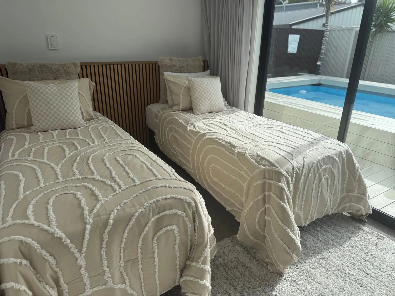 Un dormitorio con dos camas y vistas a una piscina en Sun Kissed Pool Villa - Mangawhai Heads
