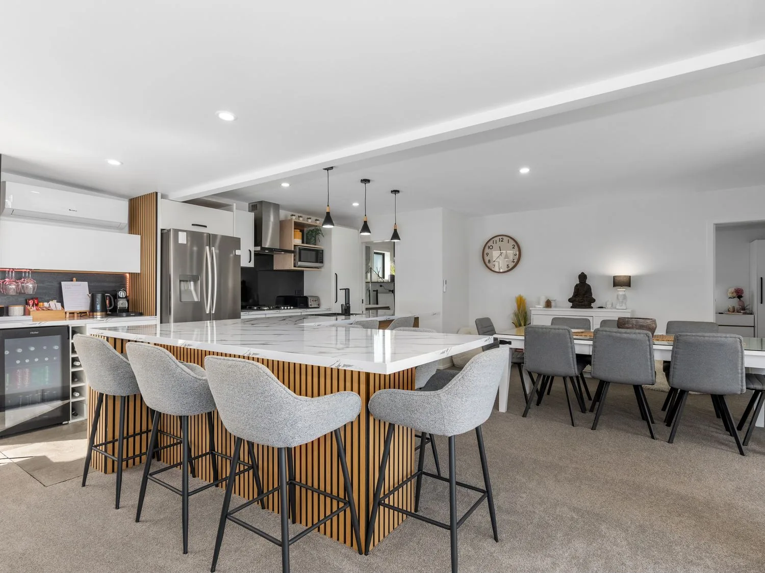 Una cocina con taburetes de barra y una mesa de comedor en Sun Kissed Pool Villa - Casa de vacaciones en Mangawhai, Mangawhai Heads